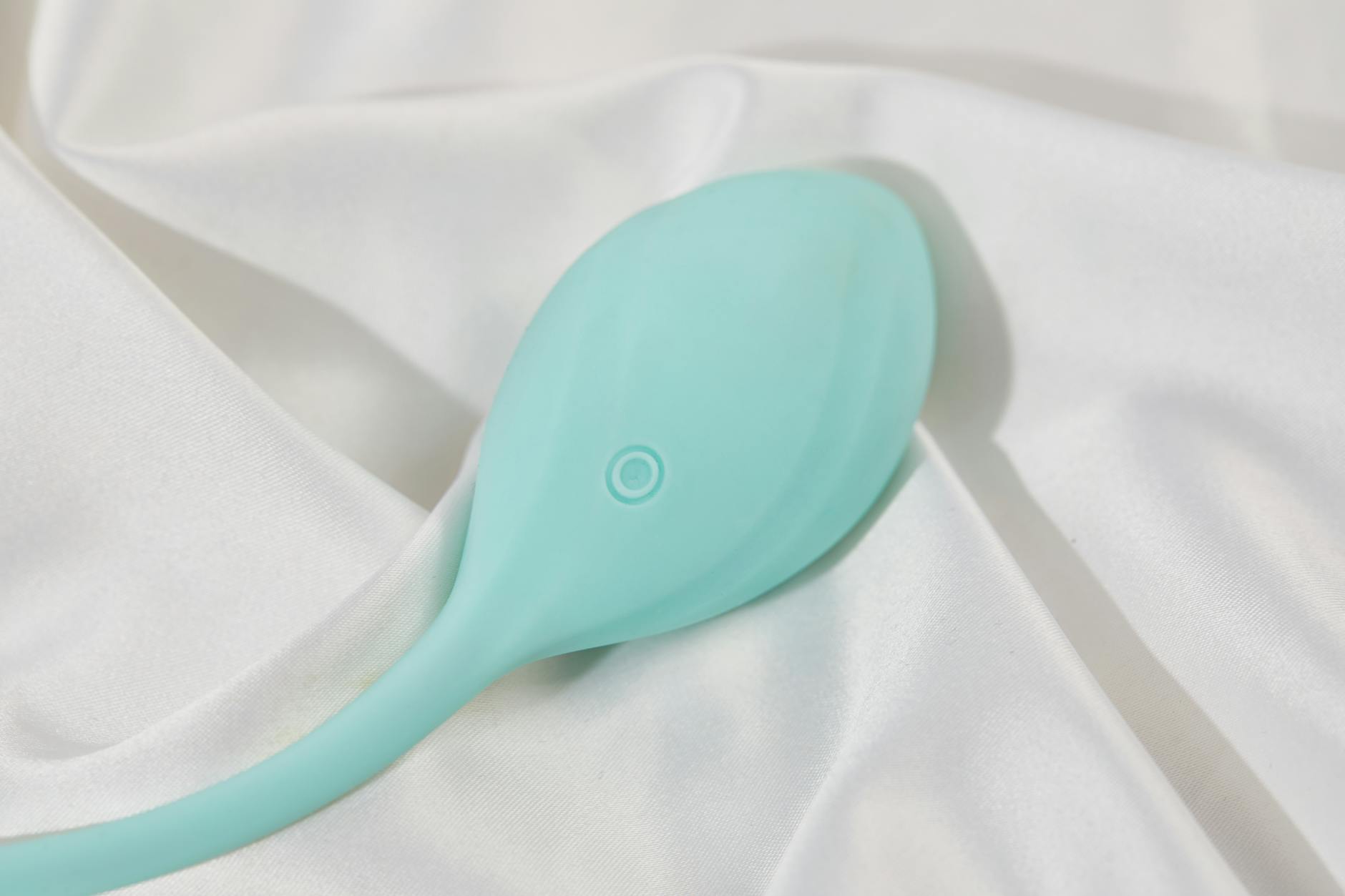 Frau mit Brille hält blaue und rosa Silikonvibratoren nachdenklich in der Hand