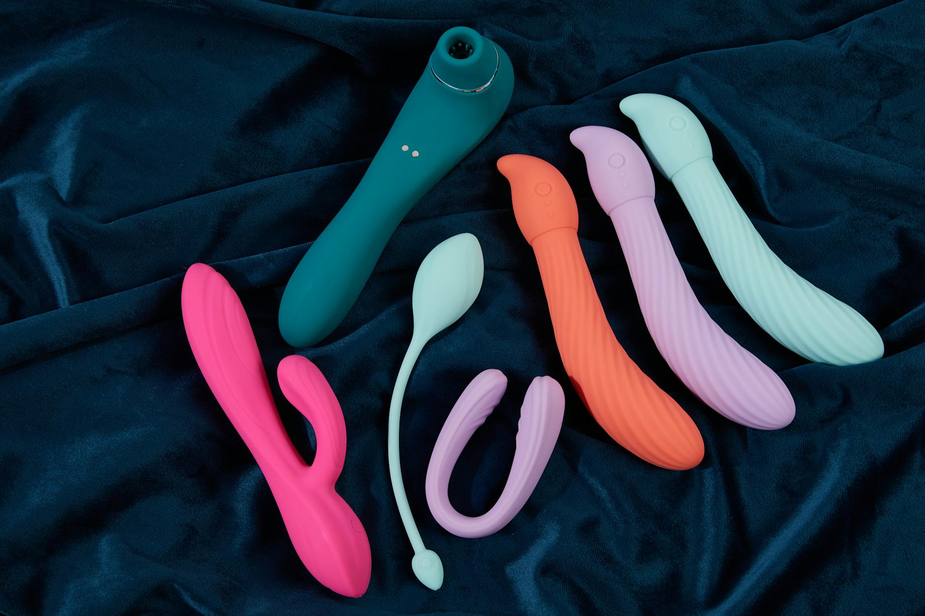 Bunte Vibratoren in verschiedenen Farben und Formen auf gelbem Hintergrund, die Vielfalt moderner Lustmittel zeigen