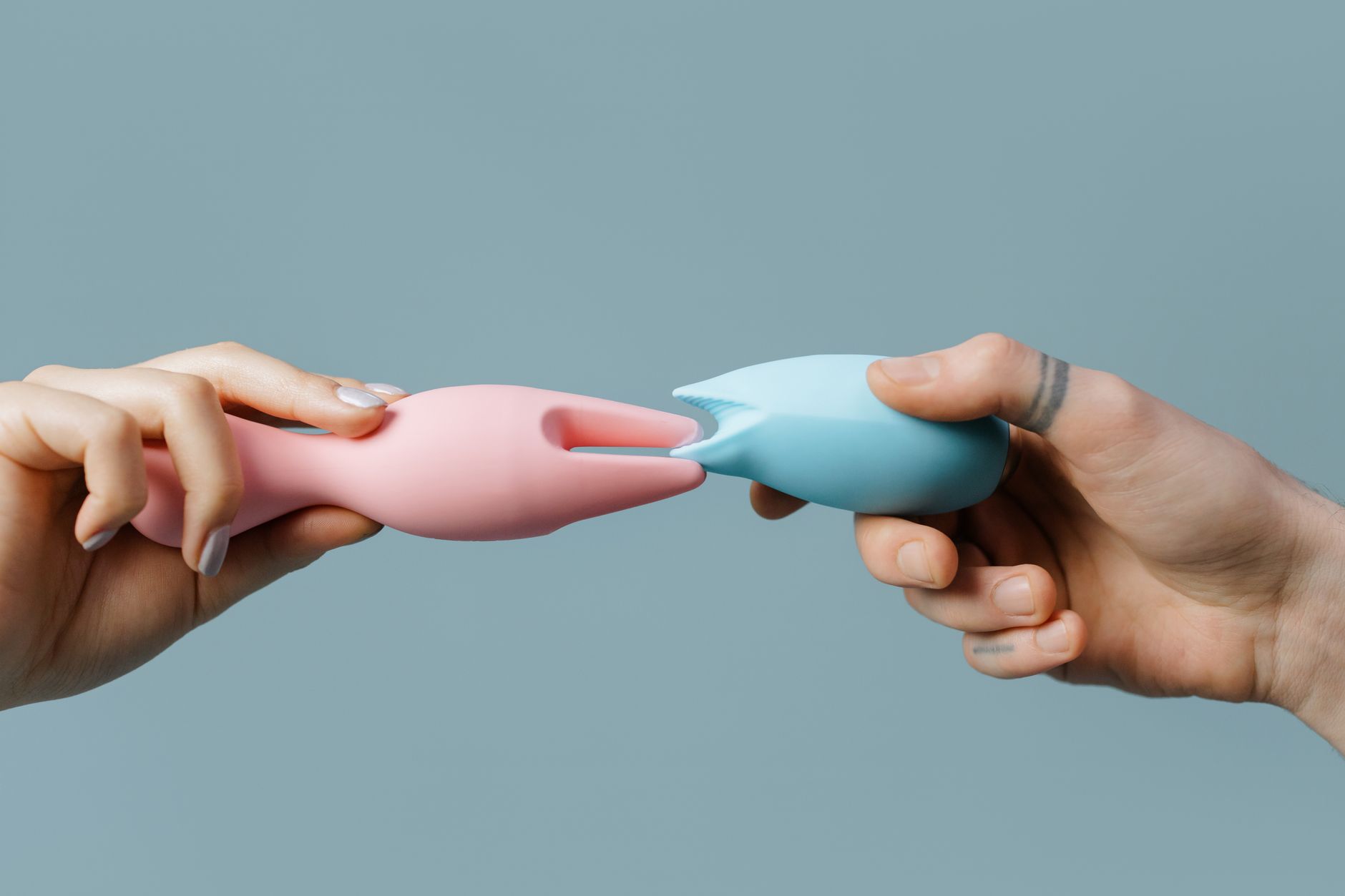Hand hält blauen Lem-Vibrator vor geknöpftem Pullover, Symbol für Selbstentdeckung nach Trennung