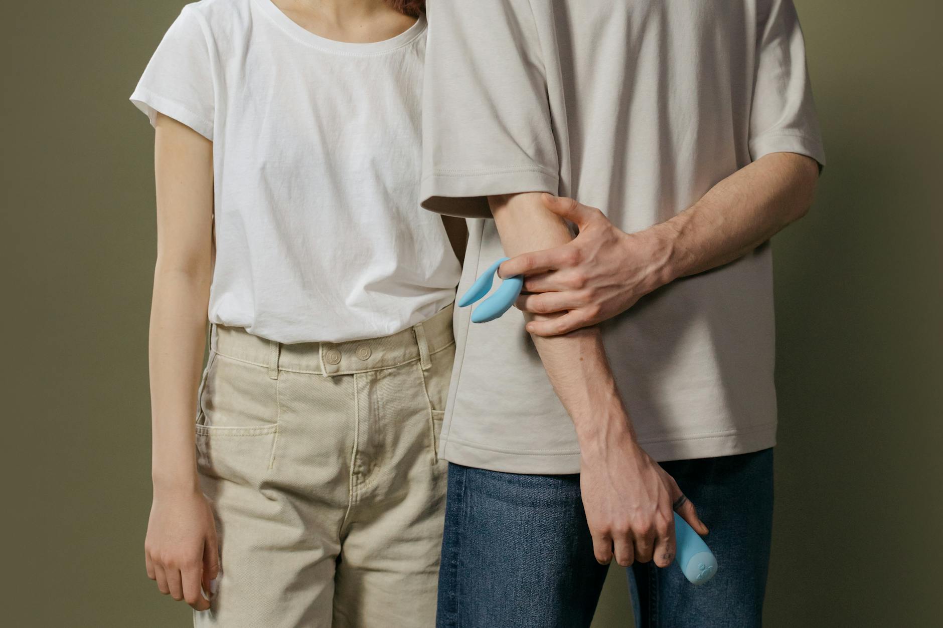 Nahaufnahme von Händen, die einen blauen persönlichen Massager gegen einen gestrickten Pullover halten