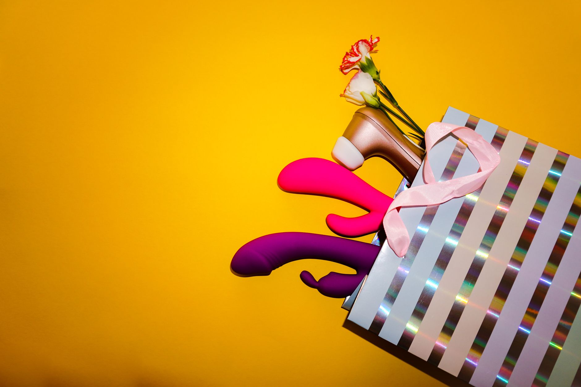 Bunte Lemon-Vibratoren in einer holographischen Geschenktasche auf gelbem Hintergrund